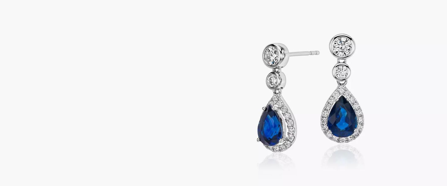 Blue pear shaped sapphire gemstones featured in a pair of dangly diamond earrings